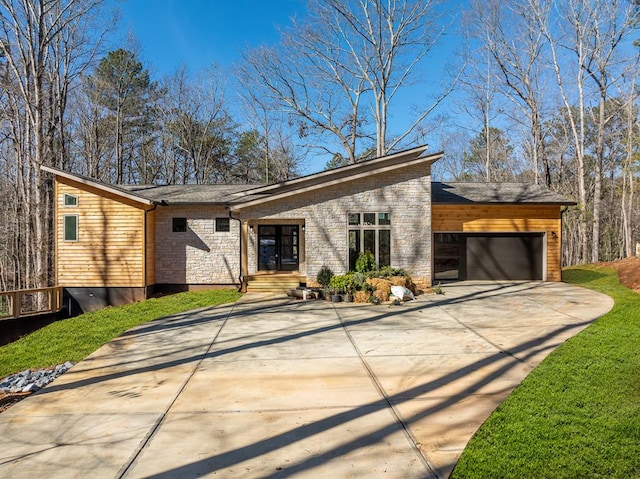 mid-century home with a garage, concrete driveway, and a front lawn