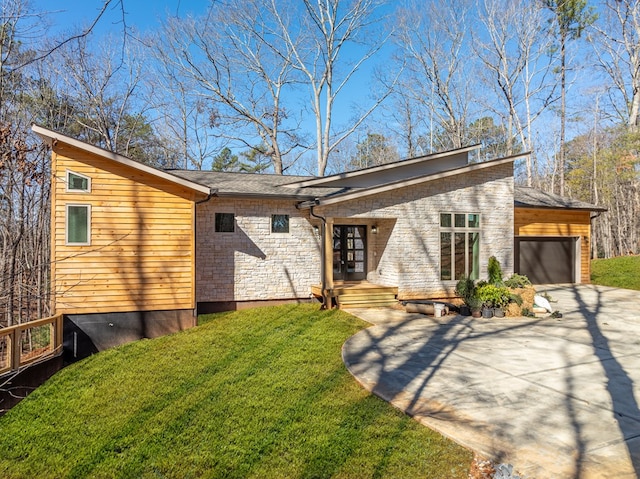 mid-century modern home with a garage, a front yard, concrete driveway, and stone siding