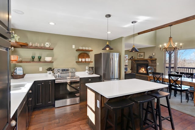 kitchen featuring a breakfast bar, dark hardwood / wood-style flooring, stainless steel appliances, and hanging light fixtures