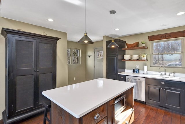 kitchen featuring dark hardwood / wood-style flooring, stainless steel appliances, sink, a kitchen island, and hanging light fixtures