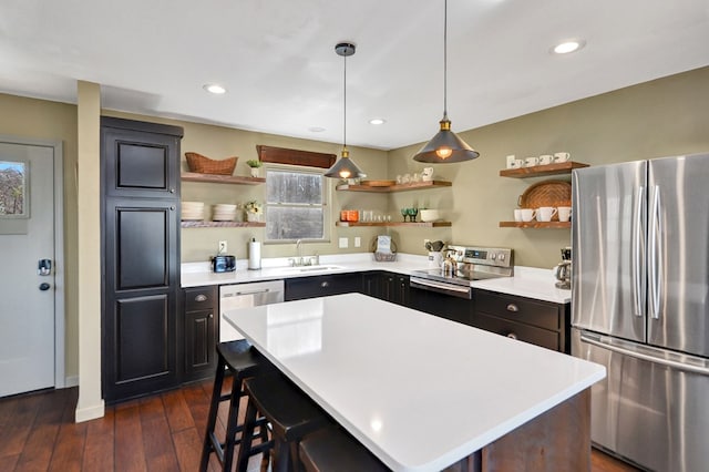 kitchen featuring sink, dark hardwood / wood-style floors, appliances with stainless steel finishes, decorative light fixtures, and a kitchen island