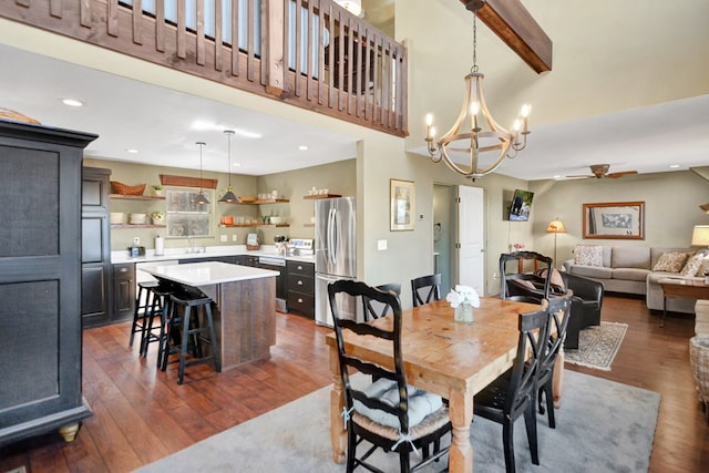 dining space with beamed ceiling, ceiling fan with notable chandelier, dark hardwood / wood-style flooring, and sink