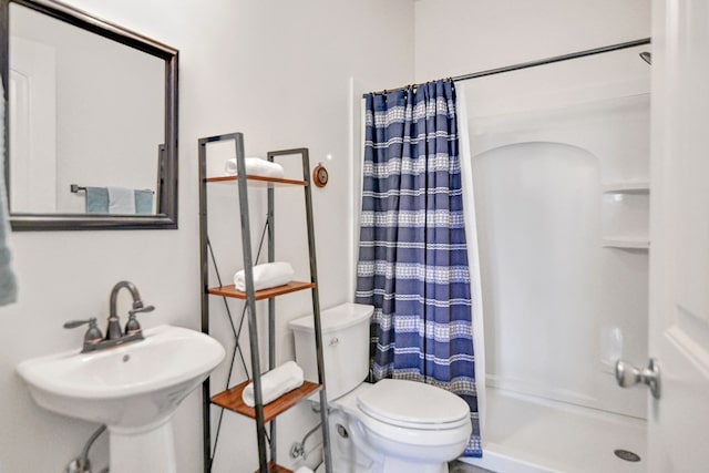 bathroom featuring a shower with curtain, toilet, and sink