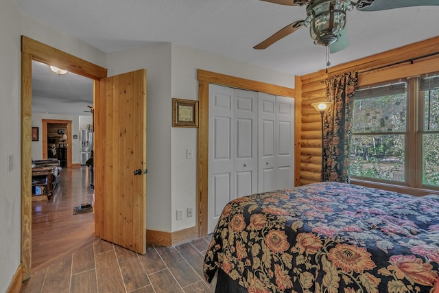 bedroom with ceiling fan, a textured ceiling, a closet, and rustic walls