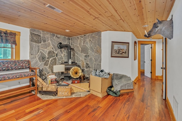 living room featuring hardwood / wood-style flooring, wooden ceiling, and a wood stove