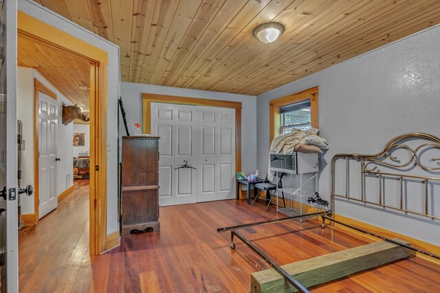 bedroom featuring hardwood / wood-style flooring, cooling unit, a closet, and wooden ceiling