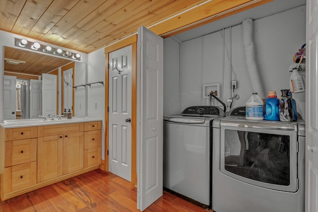 laundry room featuring washing machine and clothes dryer, wooden ceiling, and light wood-type flooring