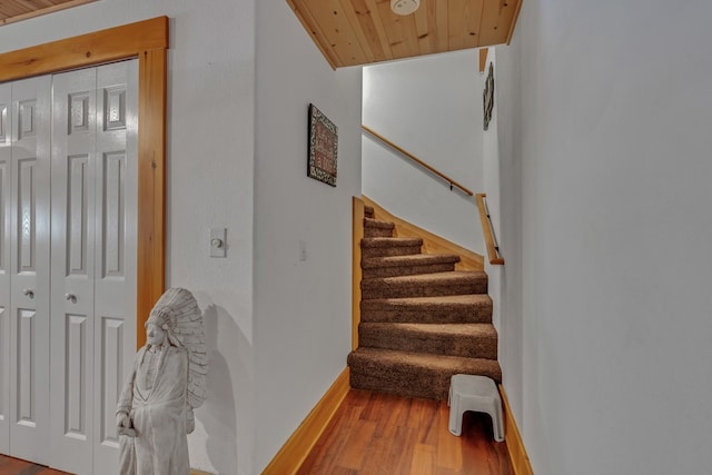 staircase featuring wood-type flooring and wooden ceiling