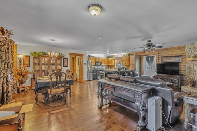 living room with hardwood / wood-style flooring, ceiling fan with notable chandelier, and a textured ceiling