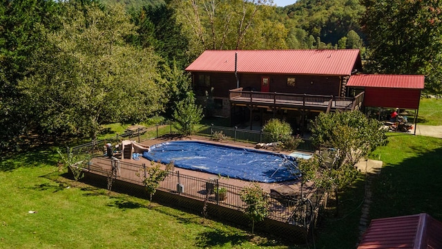 view of pool featuring a wooden deck, a water slide, and a lawn