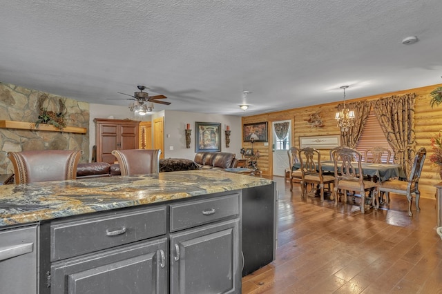 kitchen featuring pendant lighting, log walls, a textured ceiling, and hardwood / wood-style flooring