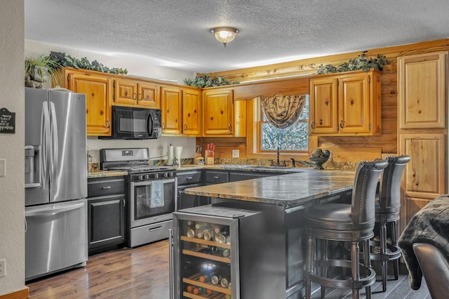 kitchen with stainless steel appliances, a breakfast bar, hardwood / wood-style floors, and a textured ceiling