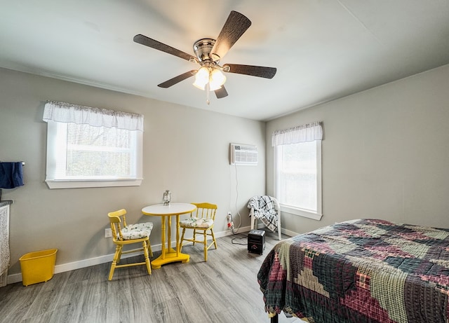 bedroom with baseboards, an AC wall unit, wood finished floors, and a ceiling fan