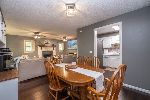 1214 Marrestop Rd, Murphy, NC 28906 - dining space with a ceiling fan, a fireplace, dark wood-style flooring, a textured ceiling, and baseboards