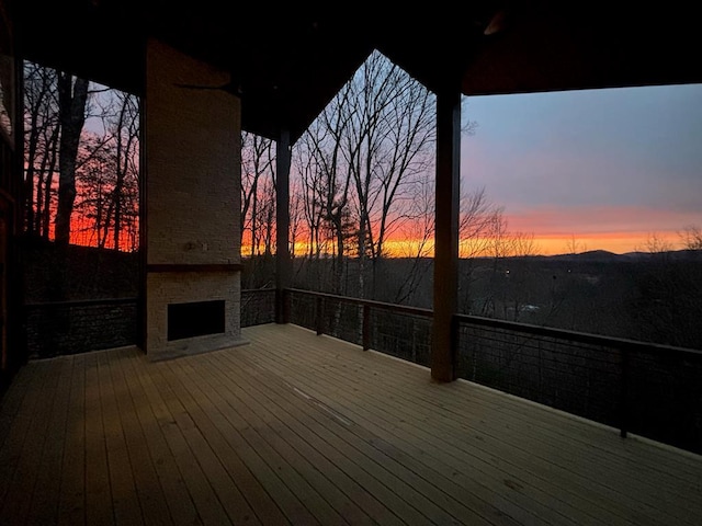 deck at dusk with ceiling fan and exterior fireplace