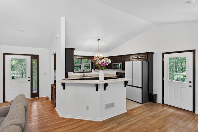 2790 Tamarack Dr, Jasper, GA 30143 - kitchen with freestanding refrigerator, vaulted ceiling, stainless steel microwave, light countertops, and a peninsula