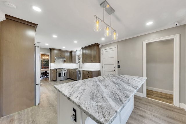 kitchen with tasteful backsplash, light stone countertops, stainless steel appliances, and a kitchen island