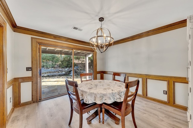 dining room with light hardwood / wood-style flooring, crown molding, and an inviting chandelier