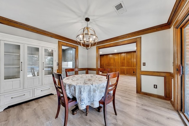 dining space featuring light hardwood / wood-style flooring, crown molding, and a notable chandelier