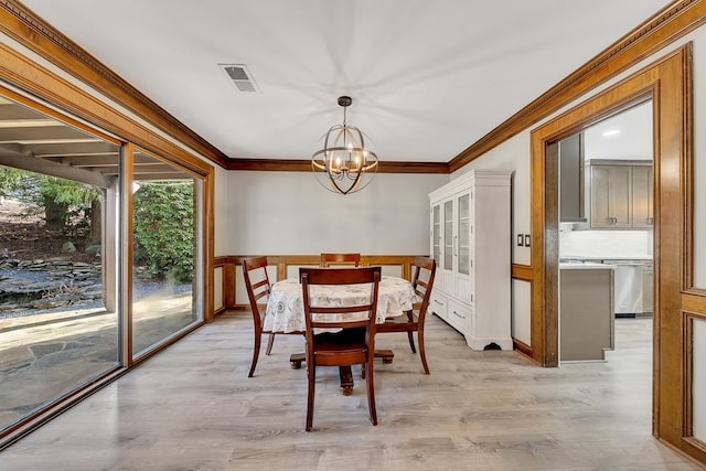 dining space featuring light hardwood / wood-style floors, crown molding, and a chandelier