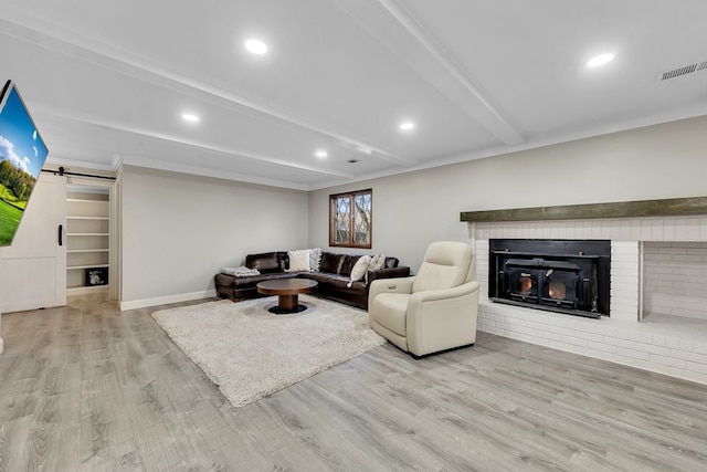 living room featuring beam ceiling, a barn door, and light wood-type flooring