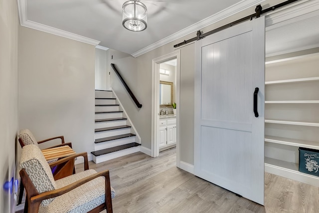 interior space with crown molding, a barn door, and light hardwood / wood-style flooring