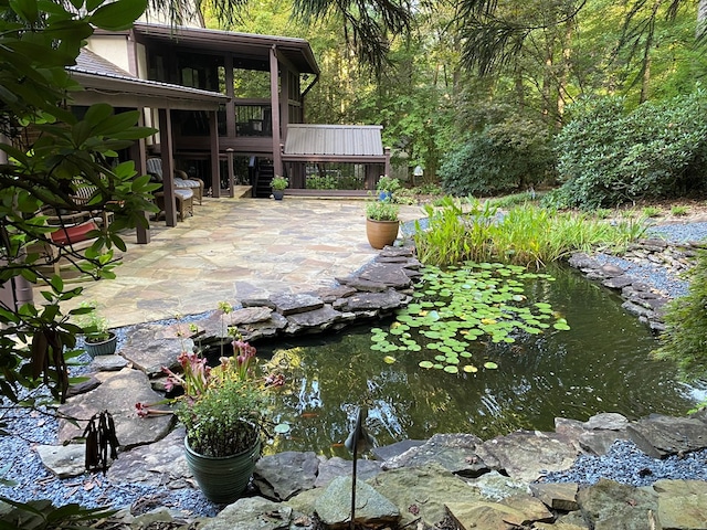 view of patio / terrace featuring a sunroom and a garden pond