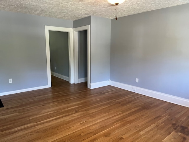 spare room featuring dark hardwood / wood-style flooring and a textured ceiling