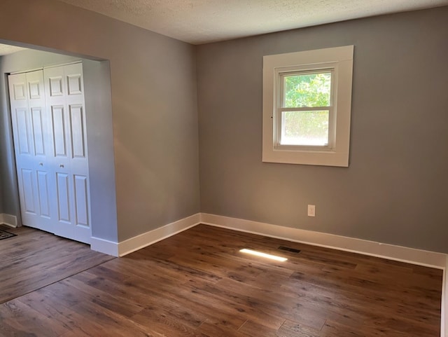 unfurnished room featuring dark wood-type flooring and a textured ceiling