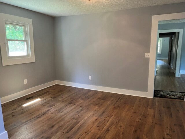 spare room with a textured ceiling and dark wood-type flooring