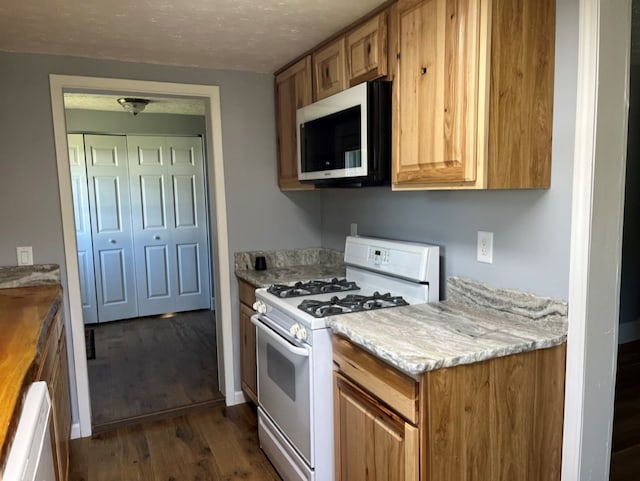 kitchen with white appliances and dark hardwood / wood-style flooring