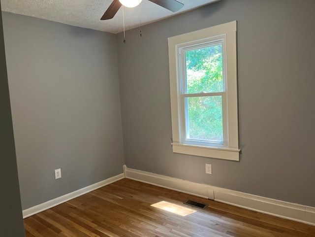 spare room with ceiling fan, a textured ceiling, and wood-type flooring