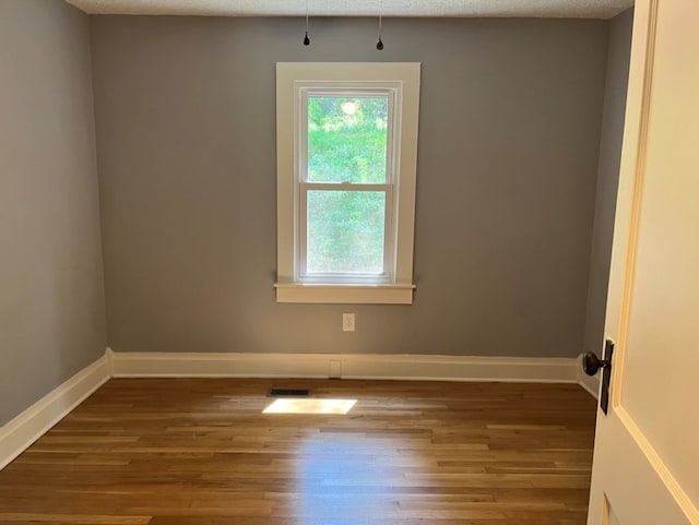 unfurnished room with a textured ceiling and hardwood / wood-style flooring