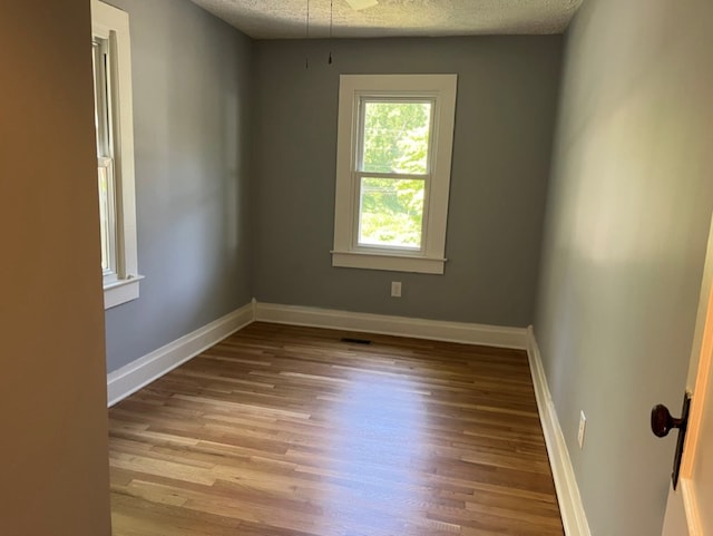 spare room with a textured ceiling and hardwood / wood-style floors