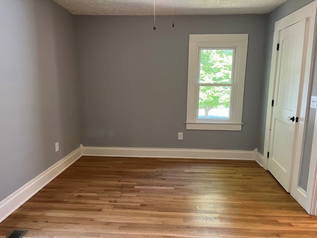 empty room with light hardwood / wood-style floors and a textured ceiling