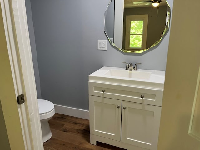 bathroom featuring ceiling fan, toilet, vanity, and wood-type flooring