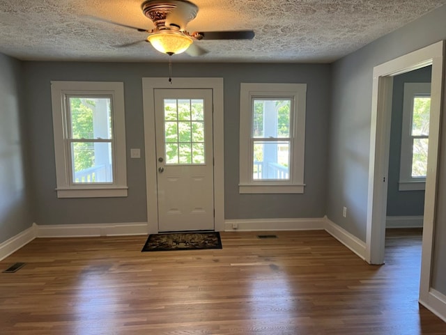 doorway with ceiling fan, a textured ceiling, and hardwood / wood-style floors