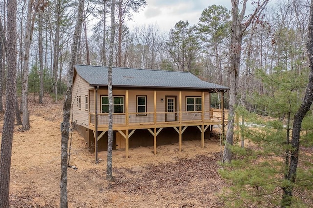 back of house with roof with shingles and a wooden deck