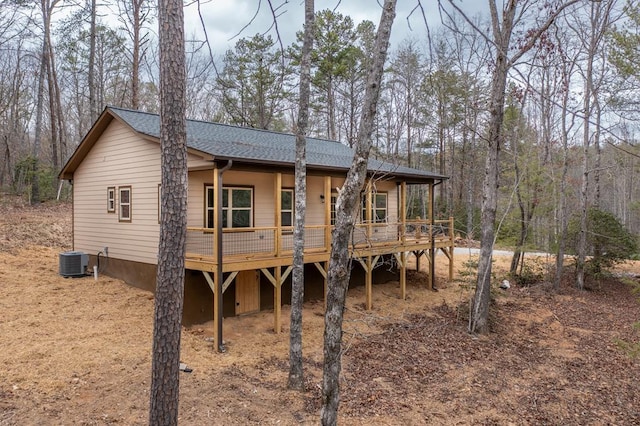 rear view of house featuring central AC, roof with shingles, and a wooden deck