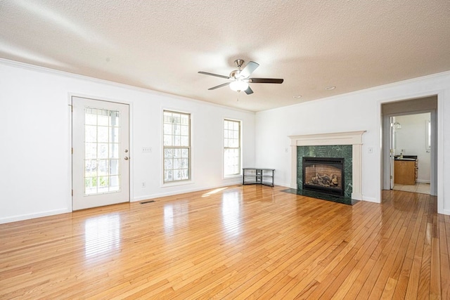 unfurnished living room with a fireplace, crown molding, light hardwood / wood-style flooring, and a textured ceiling