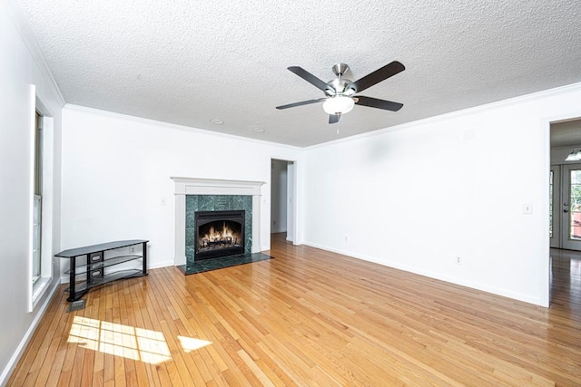 unfurnished living room featuring ornamental molding, wood-type flooring, a tiled fireplace, and a textured ceiling