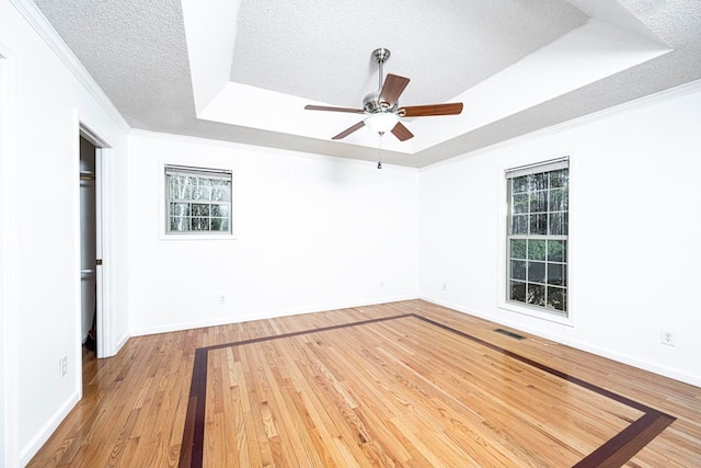 spare room featuring crown molding, a tray ceiling, a textured ceiling, and hardwood / wood-style flooring