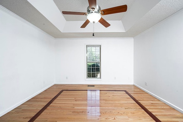 spare room with a raised ceiling, crown molding, hardwood / wood-style flooring, and a textured ceiling