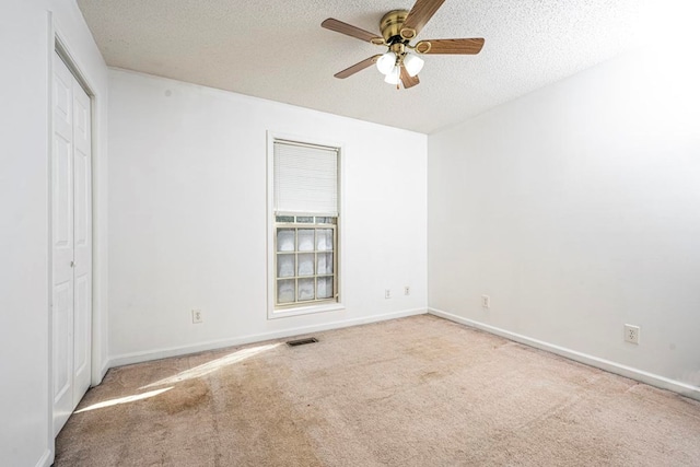 unfurnished bedroom with ceiling fan, a closet, a textured ceiling, and carpet