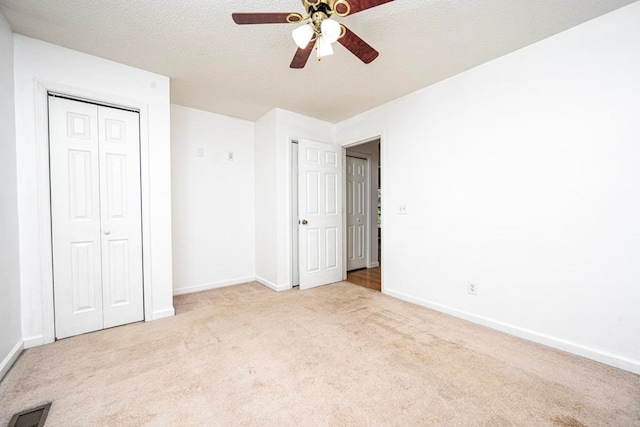 unfurnished bedroom featuring ceiling fan, light carpet, a textured ceiling, and a closet