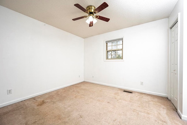 unfurnished bedroom featuring light carpet, ceiling fan, a closet, and a textured ceiling