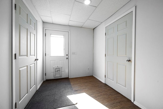 doorway to outside featuring dark wood-type flooring and a drop ceiling