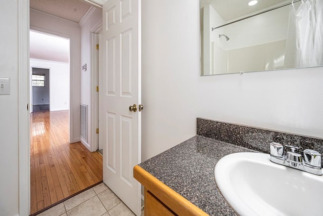 bathroom with vanity, ornamental molding, tile patterned floors, and walk in shower