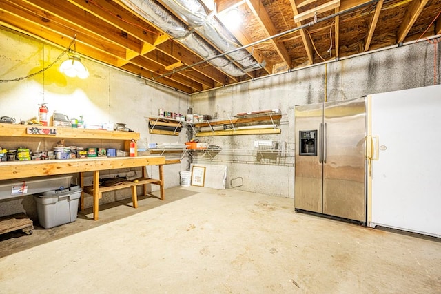 basement with a workshop area, white refrigerator, and stainless steel refrigerator with ice dispenser