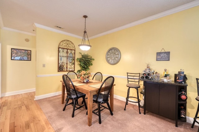 dining area featuring a textured ceiling, light hardwood / wood-style flooring, and ornamental molding